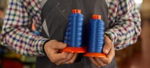 A man holding two rolls of nylon yarns- colossustex
